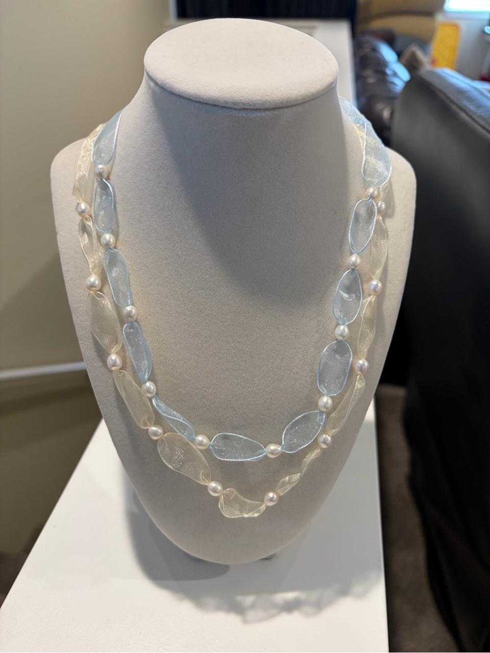 Blue and cream colored ribbon and pearl necklaces.